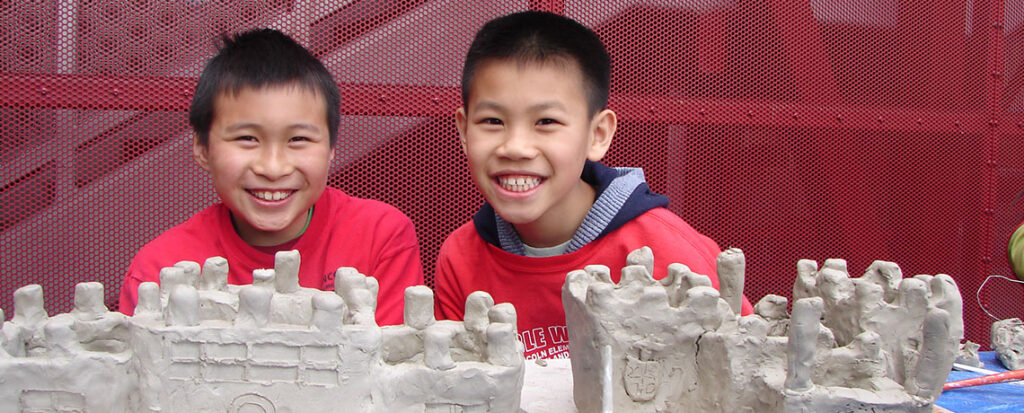 Photo of two young boys behind clay sculptures